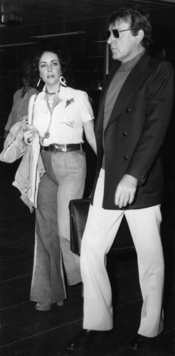 Elizabeth Taylor and her husband, Richard Burton, just can't seem to escape the camera. Passing through Rome's Leonardo da Vinci Airport June 12 for a flight to New York, they're captured on film. They'd just finished facing movie cameras for their latest films before leaving Italy. 06-12-1973