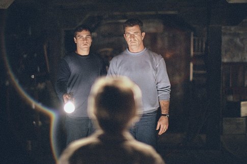 The lives of Graham Hess (Mel Gibson, right) and his brother, Merrill (Joaquin Phoenix, left) are changed forever after finding an intricate pattern of circles and lines carved into their crops