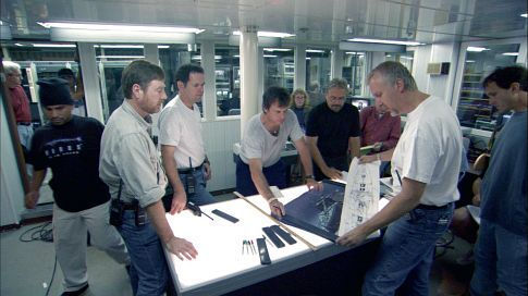 Bill Paxton (center) reviews schematics in a pre-launch discussion led by James Cameron (second from right).