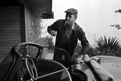 Steve McQueen at his home on Solar Drive warming up his Jaguar XK SS by placing a broomstick on the throttle
