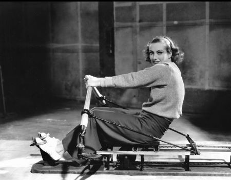 Joan Crawford exercising on a rowing machine MGM, 1933