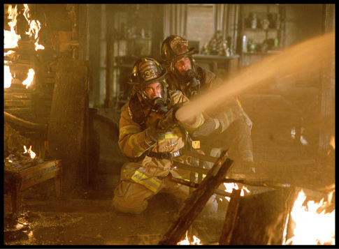 Captain Mike Kennedy (John Travolta, right) shows rookie firefighter Jack Morrison (Joaquin Phoenix, left) the ropes during his first fire.
