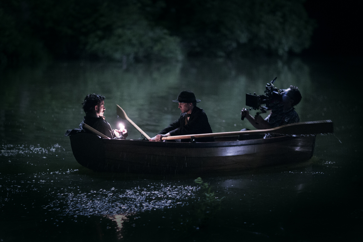 Jeremy hand holds a camera in a canoe during the filming of 