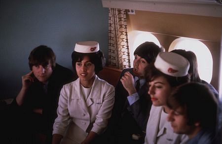 The Beatles, (John Lennon, Paul McCartney, George Harrison, Ringo Starr) in the plane with the stewardess.