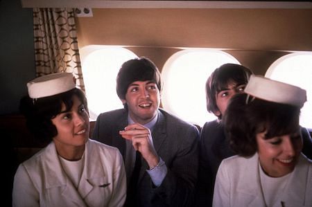 The Beatles, (Paul McCartney, George Harrison) on the plane with flight attendants, 1964