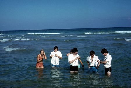 The Beatles (Paul McCartney, John Lennon, ringos Starr, George Harrison) playing in the water joined by two girls.