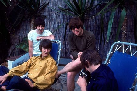 The Beatles (Paul McCartney, George Harrison, John Lennon, Ringo Starr) watch as Ringo fools around with his camera, 1964