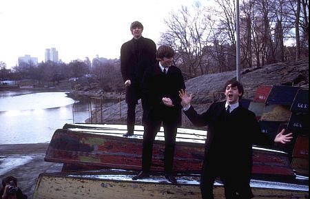 the Beatles (Ringo Starr, John Lennon, and Paul McCartney on top of some over turned boats)
