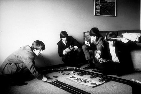 The Beatles (George Harrison, Ringo Starr, Paul McCartney and John Lennon playing with their miniature race tracks.) c. 1964