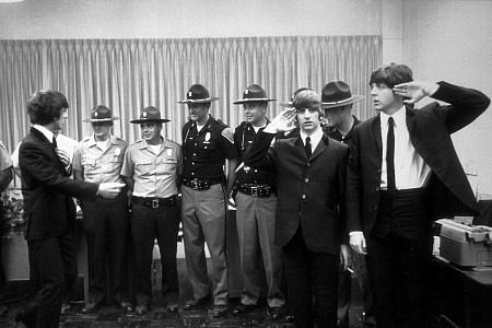 The Beatles (George Harrison, Ringo Starr, & Paul McCartney) in Indianapolis with officers as Ringo and Paul salute. c. 1964