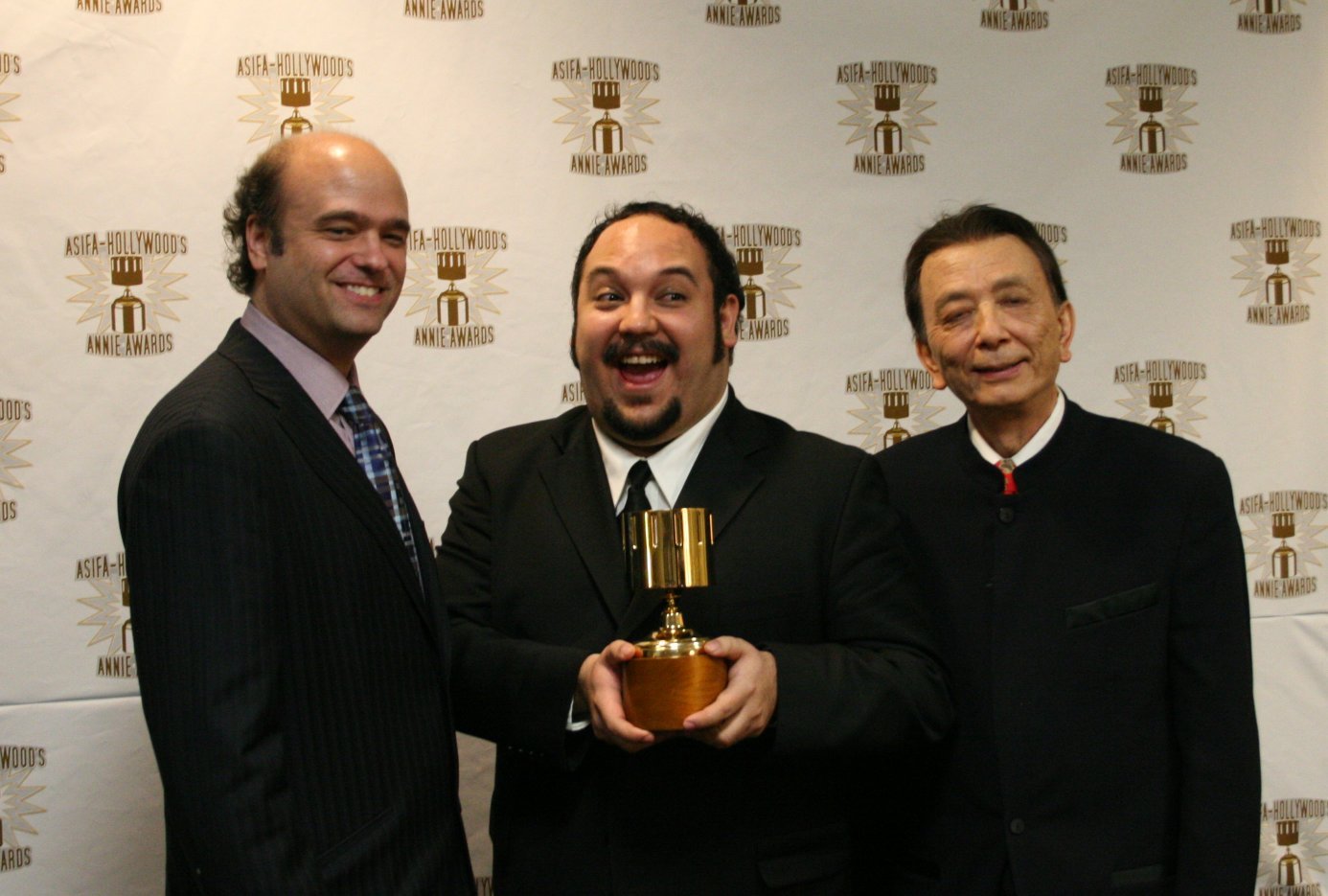 Scott Adsit (l) and James Hong (r) present the TV character design award to Jorge Gutierrez.