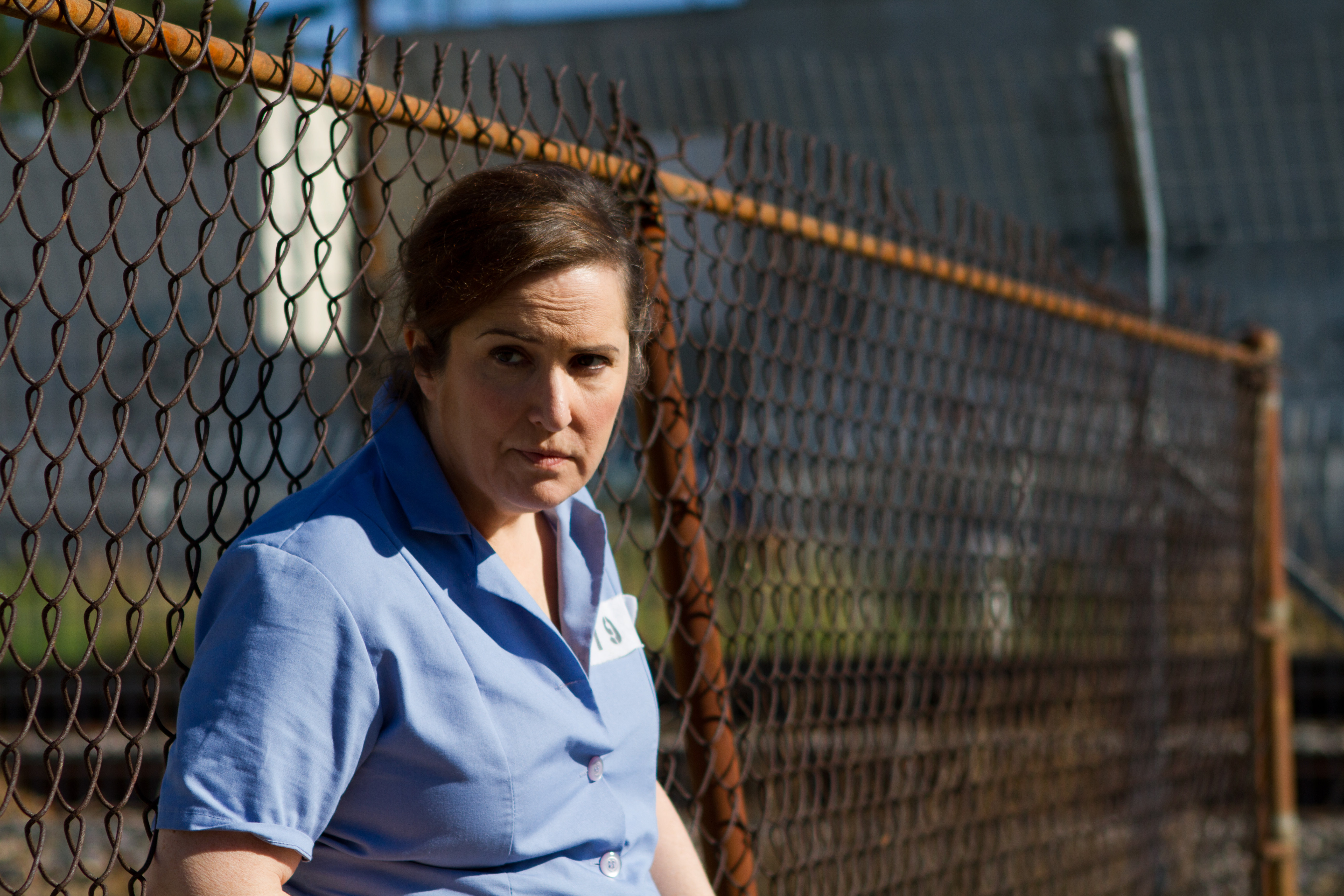 Actress/Director Jillian Armenate leans against the prison yard fence for Kittens in a Cage.