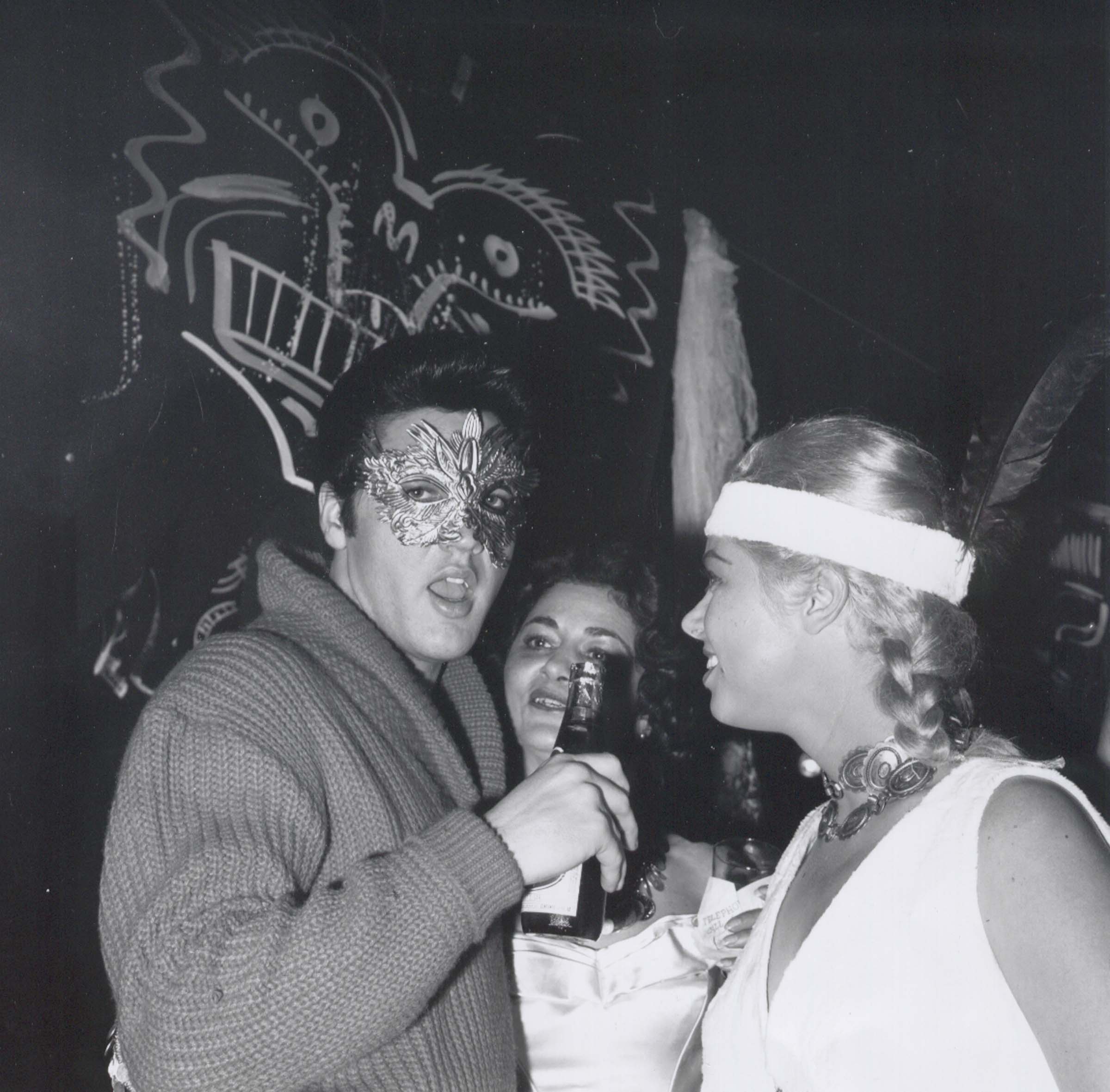 JEANNE CARMEN & ELVIS PRESLEY at SY DEVORE'S Halloween party: October 31st, 1957: Beverly Hills, California [*Note: This is the only known photo of Elvis with beer in hand] [**Note: Elvis drinks CARTA BLANCA, Cerveza fit for a King]