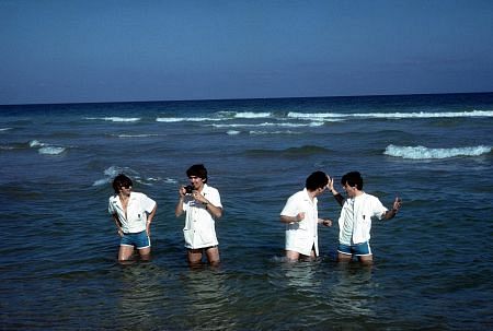 The Beatles, (Ringo Starr, George Harrison, John Lennon, Paul McCartney) playing in the water.