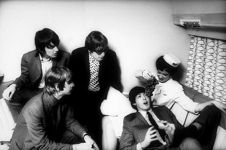 The Beatles (George Harrison, Ringo Starr, John Lennon and Paul McCartney. Paul is being fed grapes by the flight attendant) c. 1965