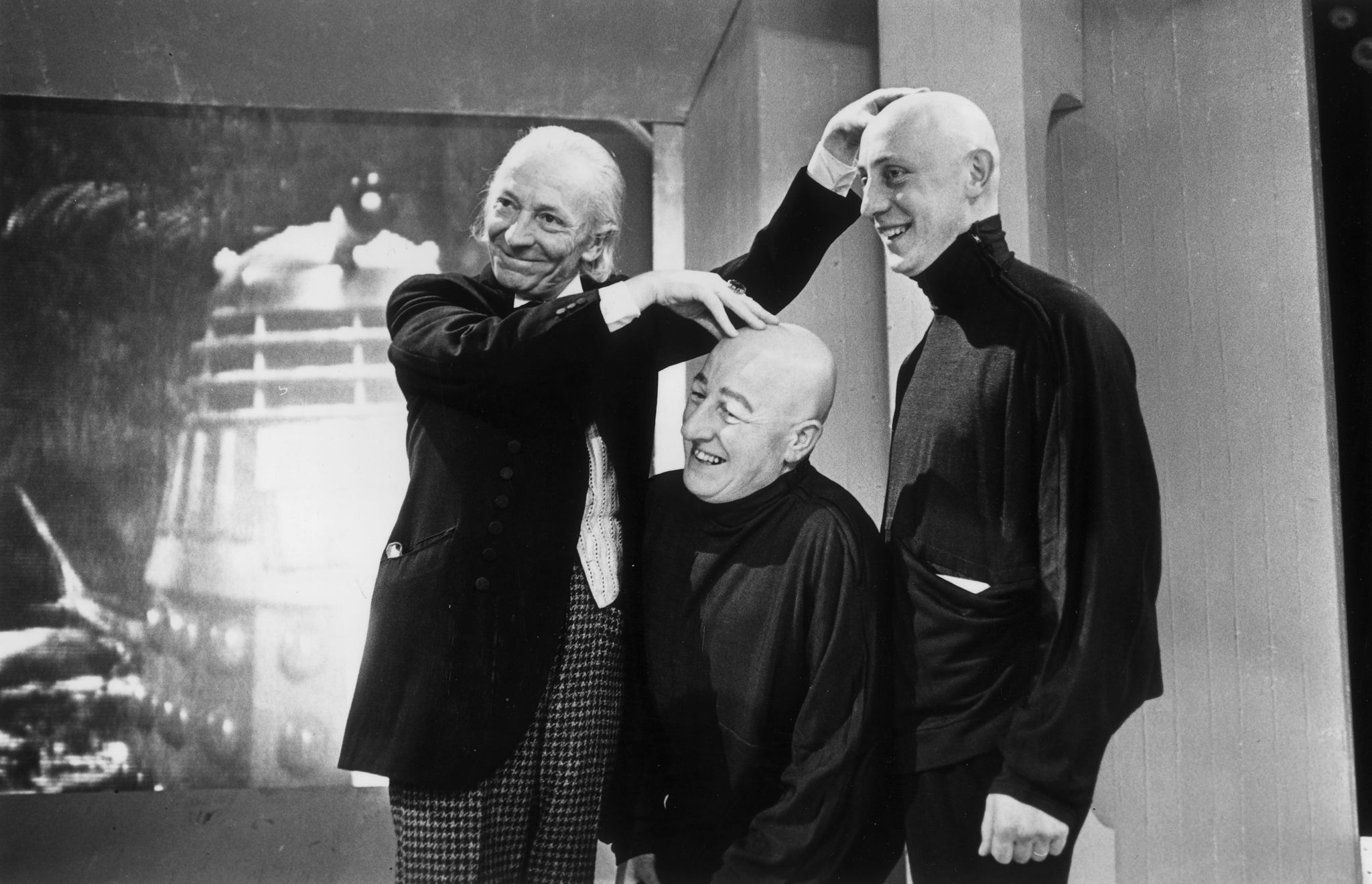1965: William Hartnell (1908 - 1975), the first incarnation of TV's Dr Who, feels the hairless pates of two ticklish co-stars. They are appearing as the Teknix, bald mutated humans employed in Space Security.