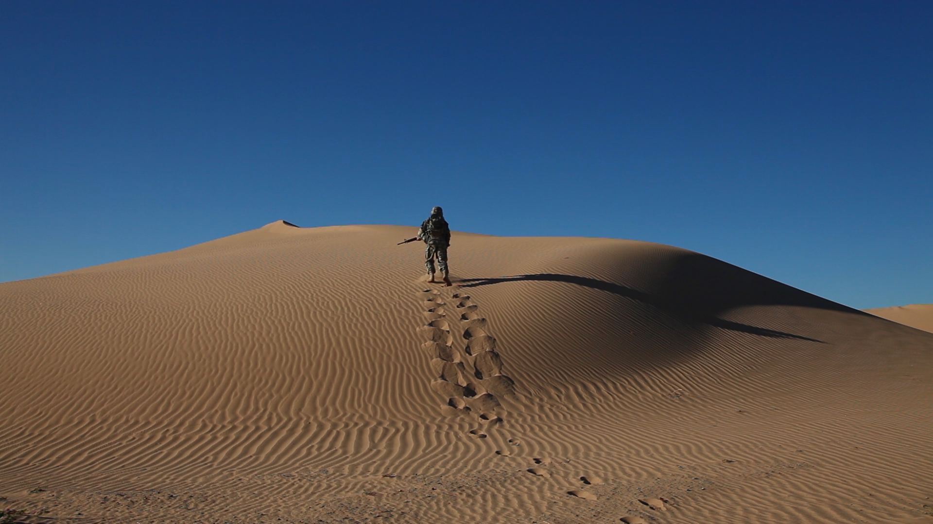 Robert Mann as The Soldier climbing up mountain of sand in the 2013 film, The Soldier: The Search for Existence.