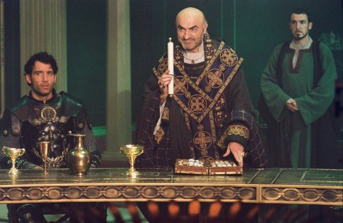 Arthur (Clive Owen, left) listens as Bishop Germanius (Ivano Marescotti, center) requests a final challenge of Arthur's Knights of the Round Table while Horton (Pat Kinevane, right) looks on.