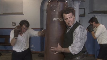 John Noble portrays world famous boxing manager and trainer Eddie Thomas, holding the bag for his prodigy Howard Winstone (Stuart Brennan).