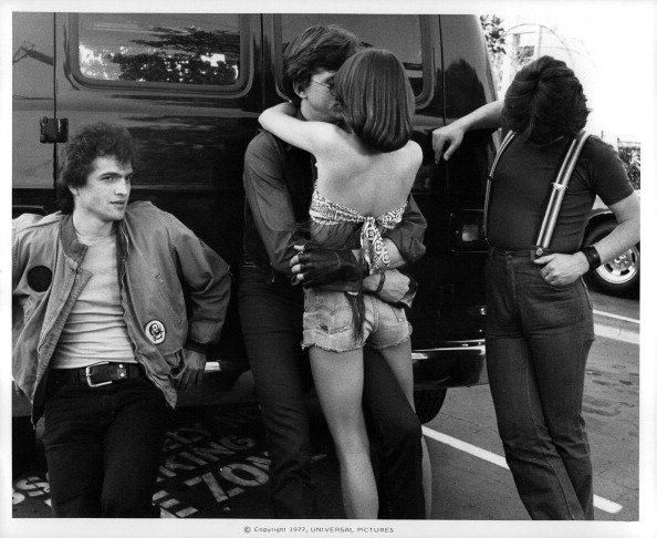 David Wilson (C) embracing Donna Wilkes while Allen G. Norman and John Kirby (R) look on in a scene from the film 'Almost Summer', 1978. (Photo by Universal Pictures/Getty Images)