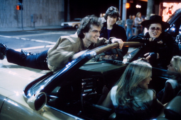 Allen G. Norman (L) laughing while laying on a car hood in which Yvette Sylvander and Yvonne Sylvander sit as John Kirby (C) and David Wilson look on in a scene from the film 'Almost Summer', 1978. (Photo by Universal Pictures/Getty Images)