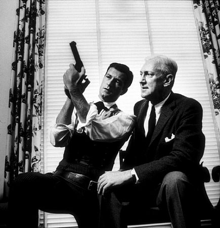 Hugh O'Brien and Pete Martin looking at a prop gun from O'Brien's TV show, 