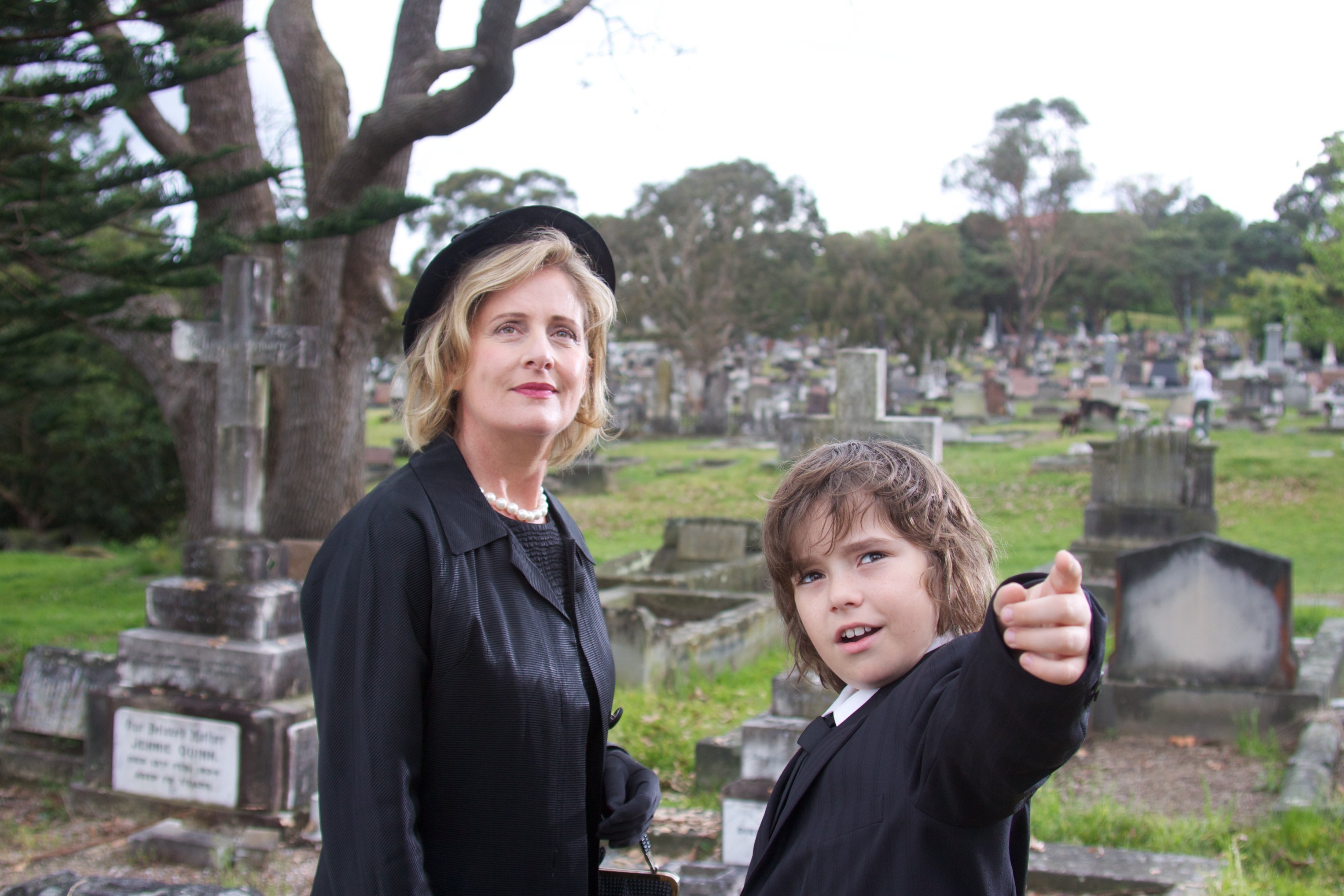 Miss Judy (Sonia Todd) and Joshua (Karl Beattie) at the funeral.