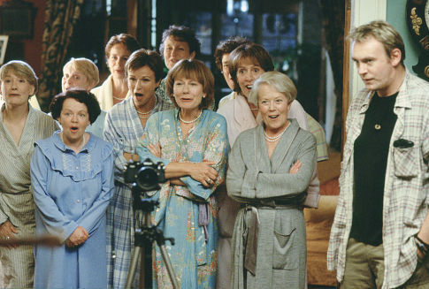 The women of Knapely (left to right, front row: Lesley Staples, Angela Curran, Julie Walters, Rosalind March, Penelope Wilton, Annette Crosbie. left to right, back row: Janet Howd, Celia Imrie, Georgie Glen, Linda Bassett) prepare to bare all for their photographer, Lawrence (Philip Glenister, right).