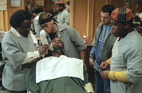 MICHAEL EALY (Ricky), TROY GARITY (Isaac), and LEONARD HOWZE (Dinka) look on (center left to right) while CEDRIC THE ENTERTAINER (Eddie, far left) gives a shave