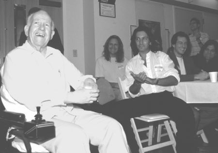 John Chambers (left) greets guests as he enters his surprise 75th birthday party on September 12, 1997 at the Motion Picture Home in Woodland Hills, CA. Seated from left in the photo are creature/makeup artists Jake Garber, Patrick Tatopoulos, Bill Corso, and Steve Neill.