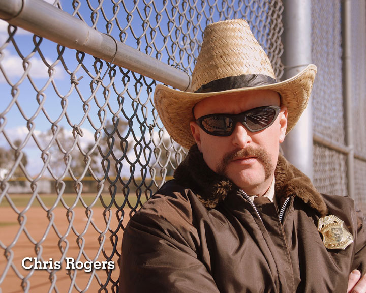 Chris Rogers State Trooper in front of chain link fence.