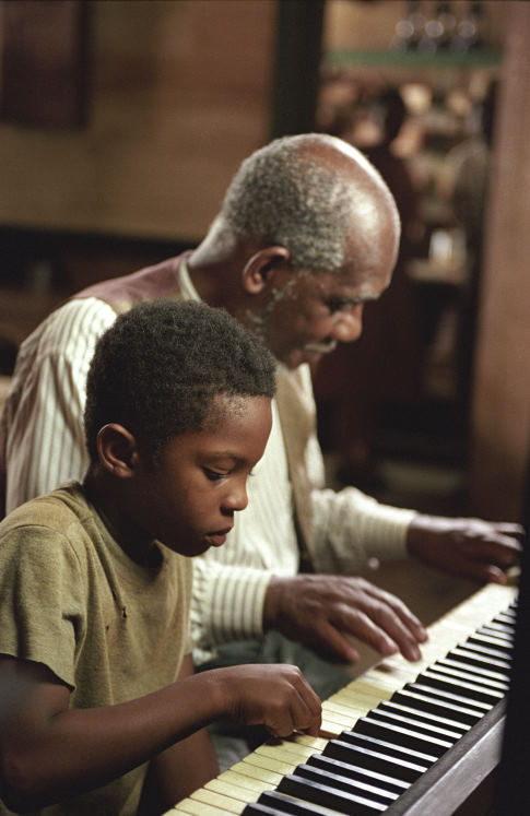 A young Ray Charles (C.J. SANDERS, left) begins to learn piano in the musical biographical drama, Ray.