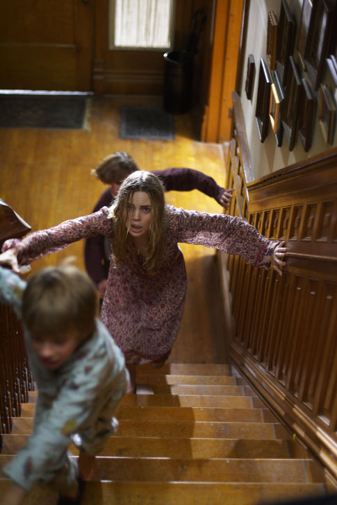 Kathy (MELISSA GEORGE) flees upstairs with her children Chris (JIMMY BENNETT) and Billy (JESSE JAMES) in THE AMITYVILLE HORROR.