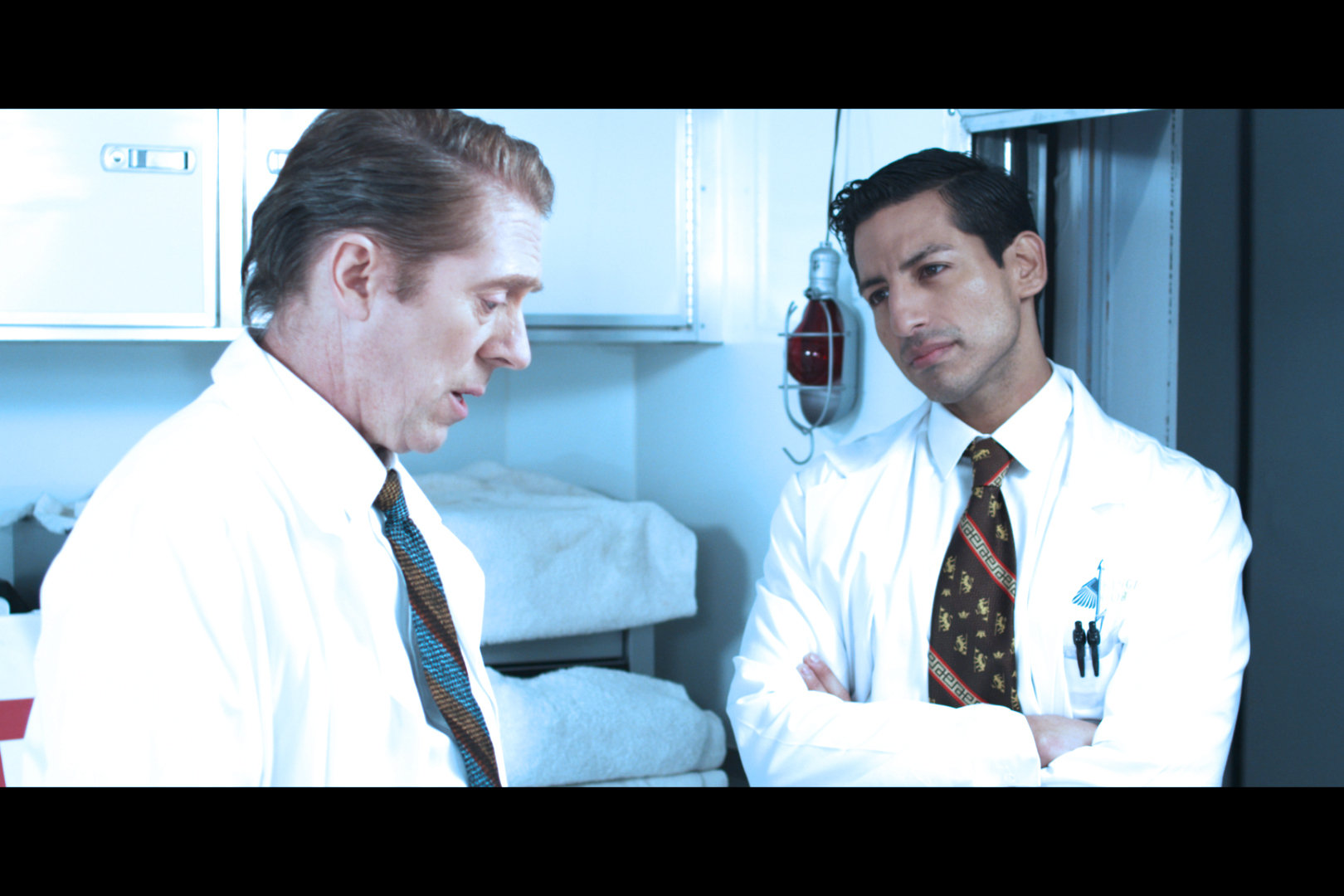 Felix (Alex Kruz) explaining to Dr. Greenglass (Allen Enlow) his reasoning behind using live test subjects 