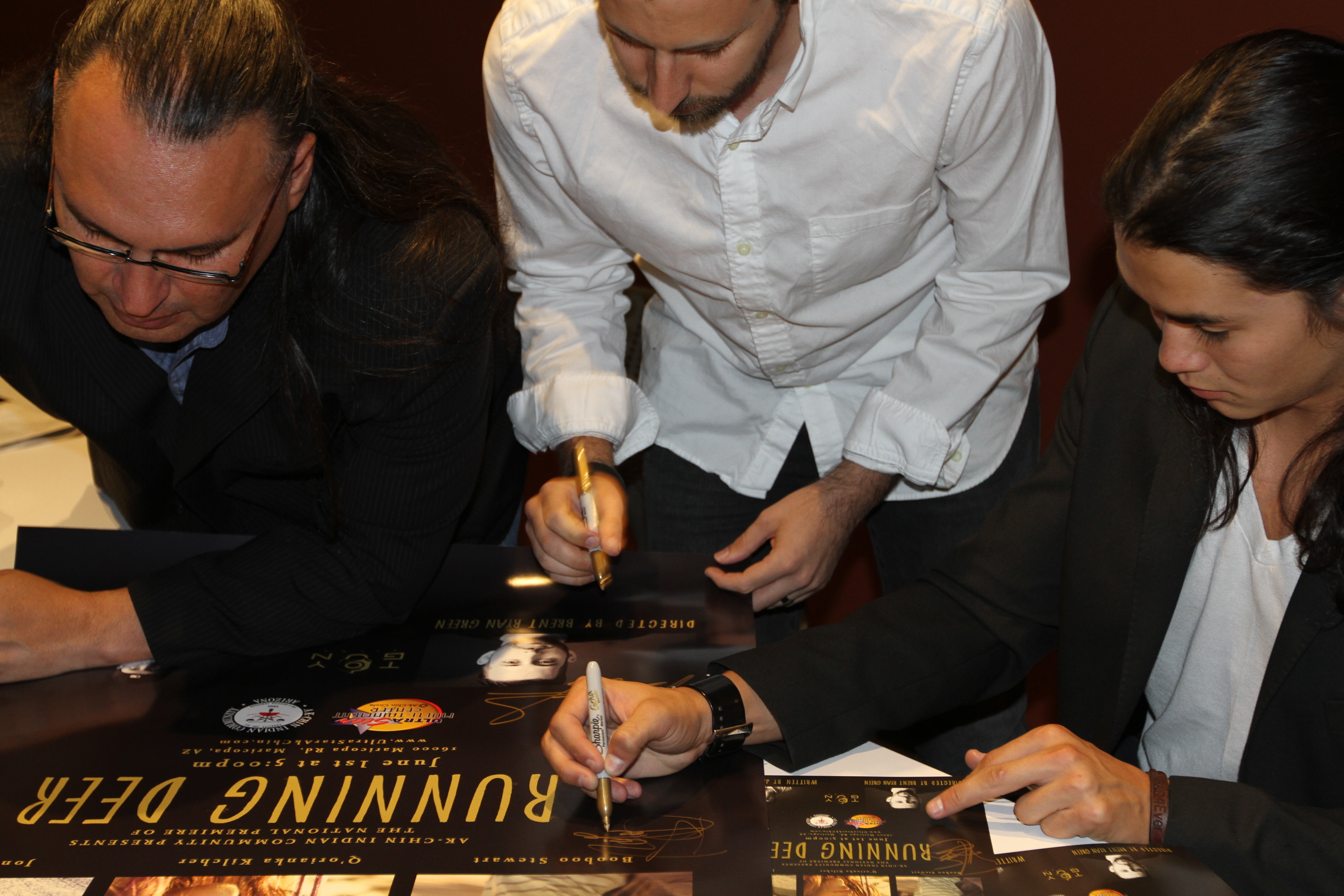 Jon Proudstar, Brent Ryan Green and Booboo Stewart autographing a poster following the premiere of Running Deer