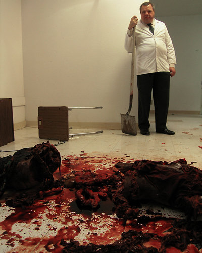 Doctor Gabriel Schreklich (Louis Graham) looks over the remains of failed patient.