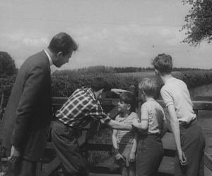 The Vicar (William Russell) chasing Naughty Boy (Christopher Toyne) and Titch (Ian Higginson) vaults a high gate, giving the village boys the idea of asking him to coach their athletics, in order to win back Hal 5.