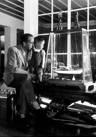 Humphrey Bogart and his son, Stephen, looking at a model of his yacht, 