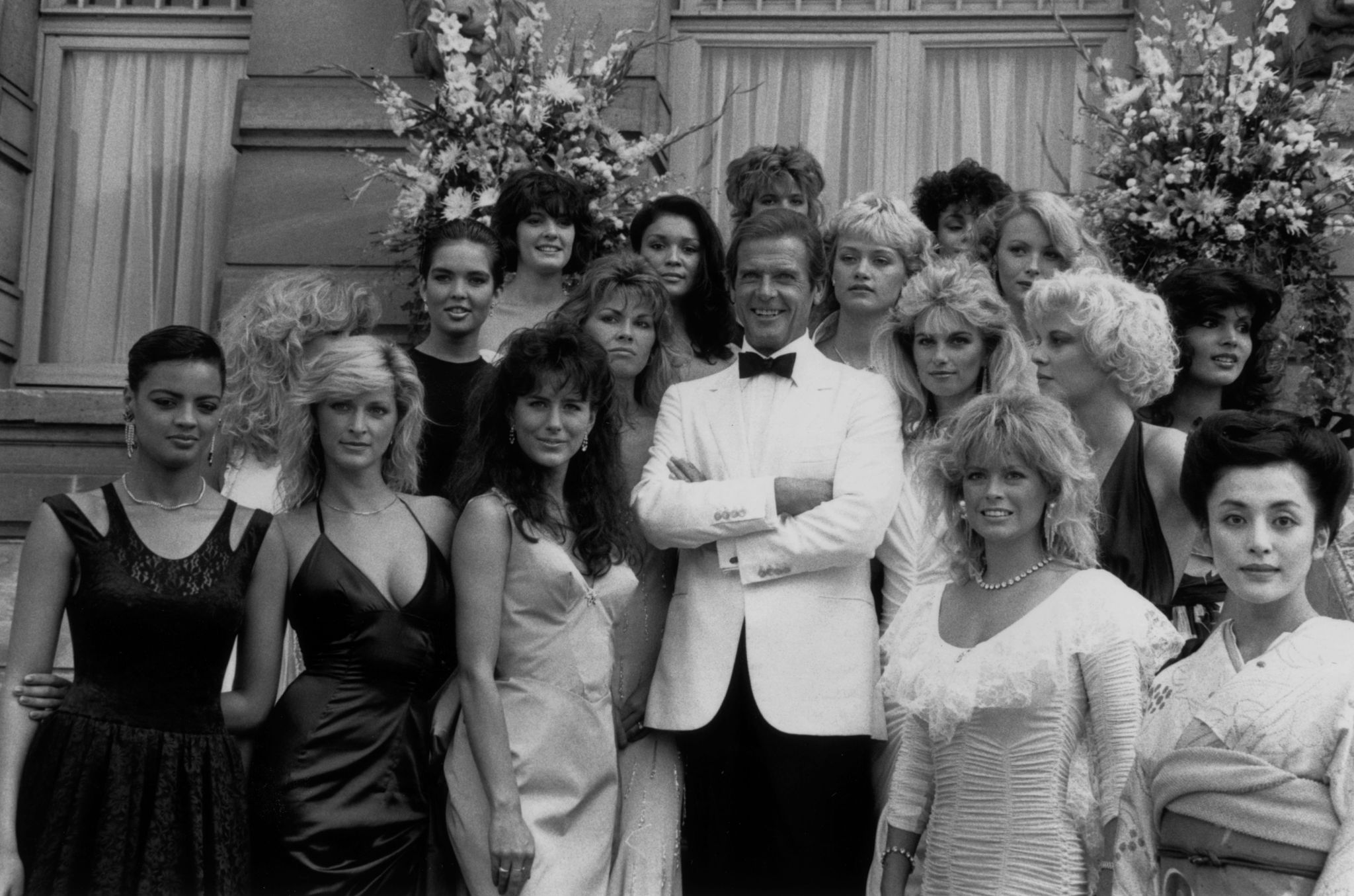 Still of Roger Moore, Sian Adey-Jones, Nike Clark, Gloria Douse, Caroline Hallett, Patricia Martínez, Lou-Anne Ronchi, Paula Thomas, Mayako Torigai, Terri Johns, Jane Spencer, Kim Ashfield Norton, Celine Cawley and Karen Loughlin in Zvilgsnis i zmogzudyste (1985)