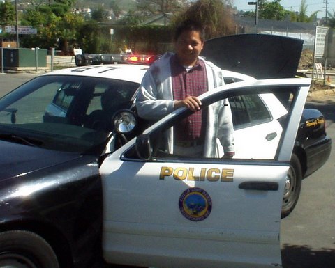 Actor Edmund K Lo is getting out of the Police Car at Long Beach City College in Long Beach, Ca & wave hello to fan. The Police Car is from the Long Beach City Police Department.
