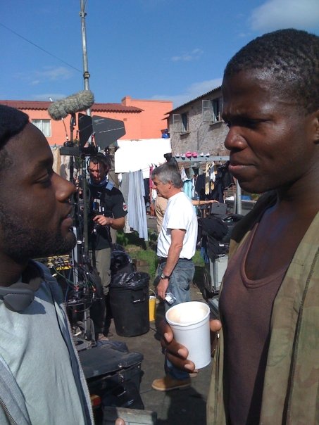 Vladimir Versailles giving actor Reno Wilson note on set.