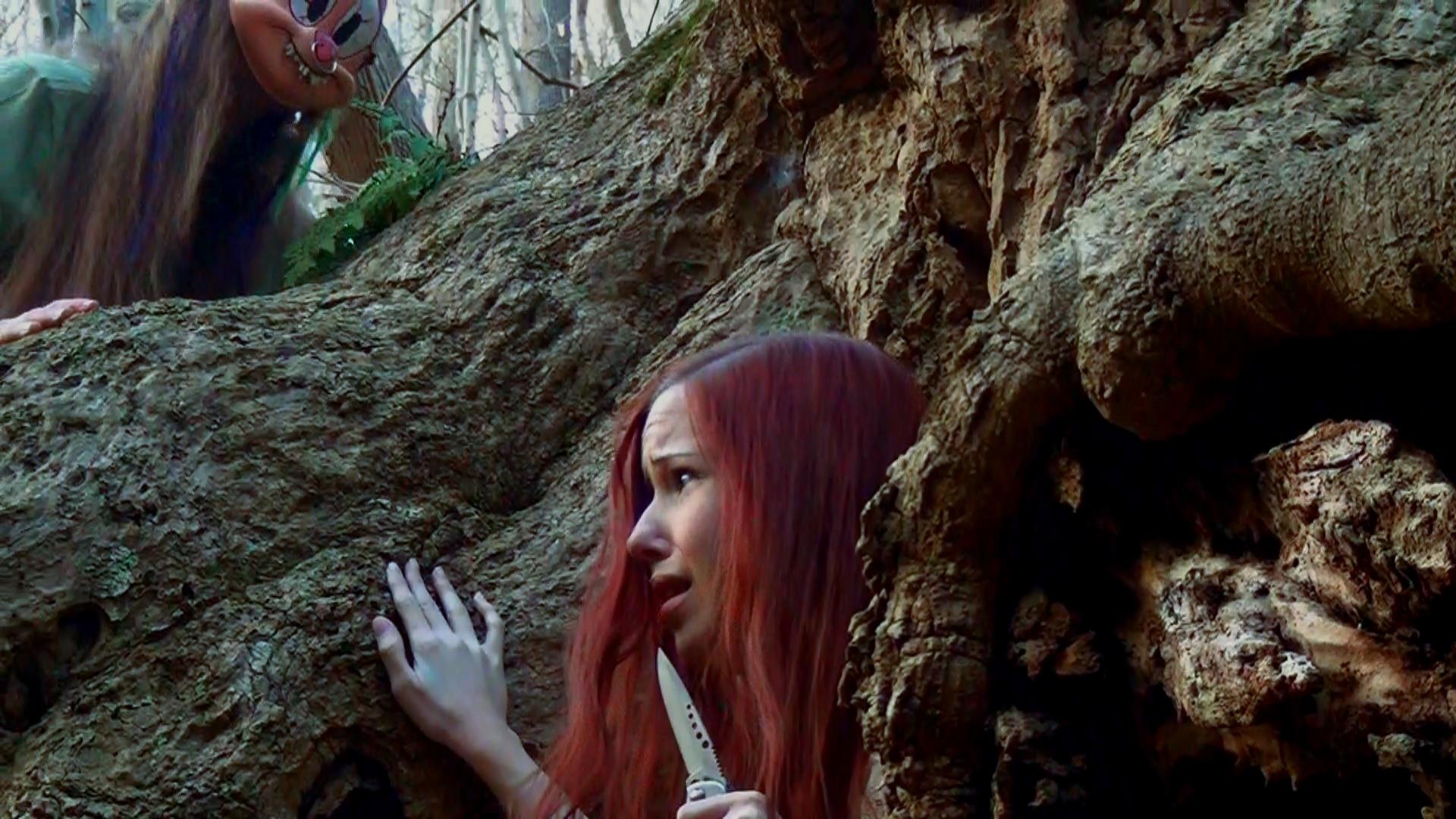 Heather (Kaylee Williams) hides behind a tree in 