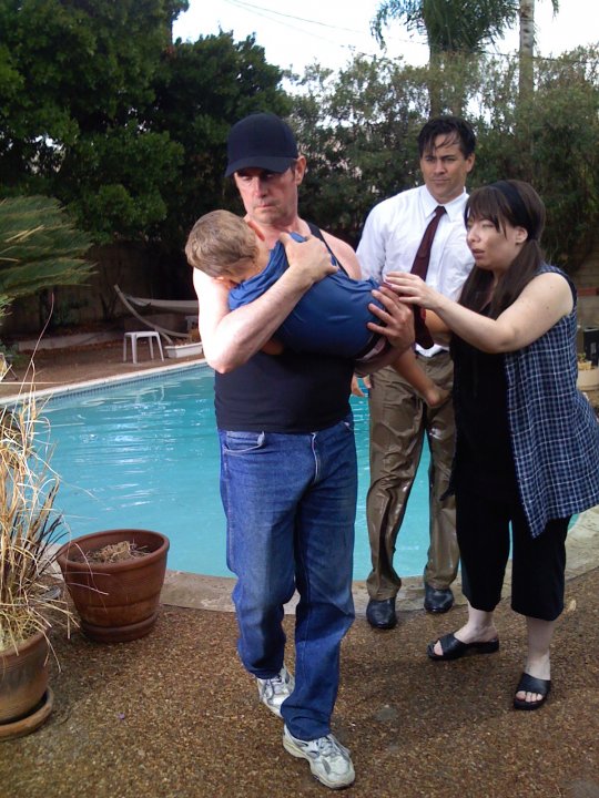 Thom Michael Mulligan (Pete Young)Carries young son from swimming pool in a movie still from the Multi Award Winning Feature film Callous