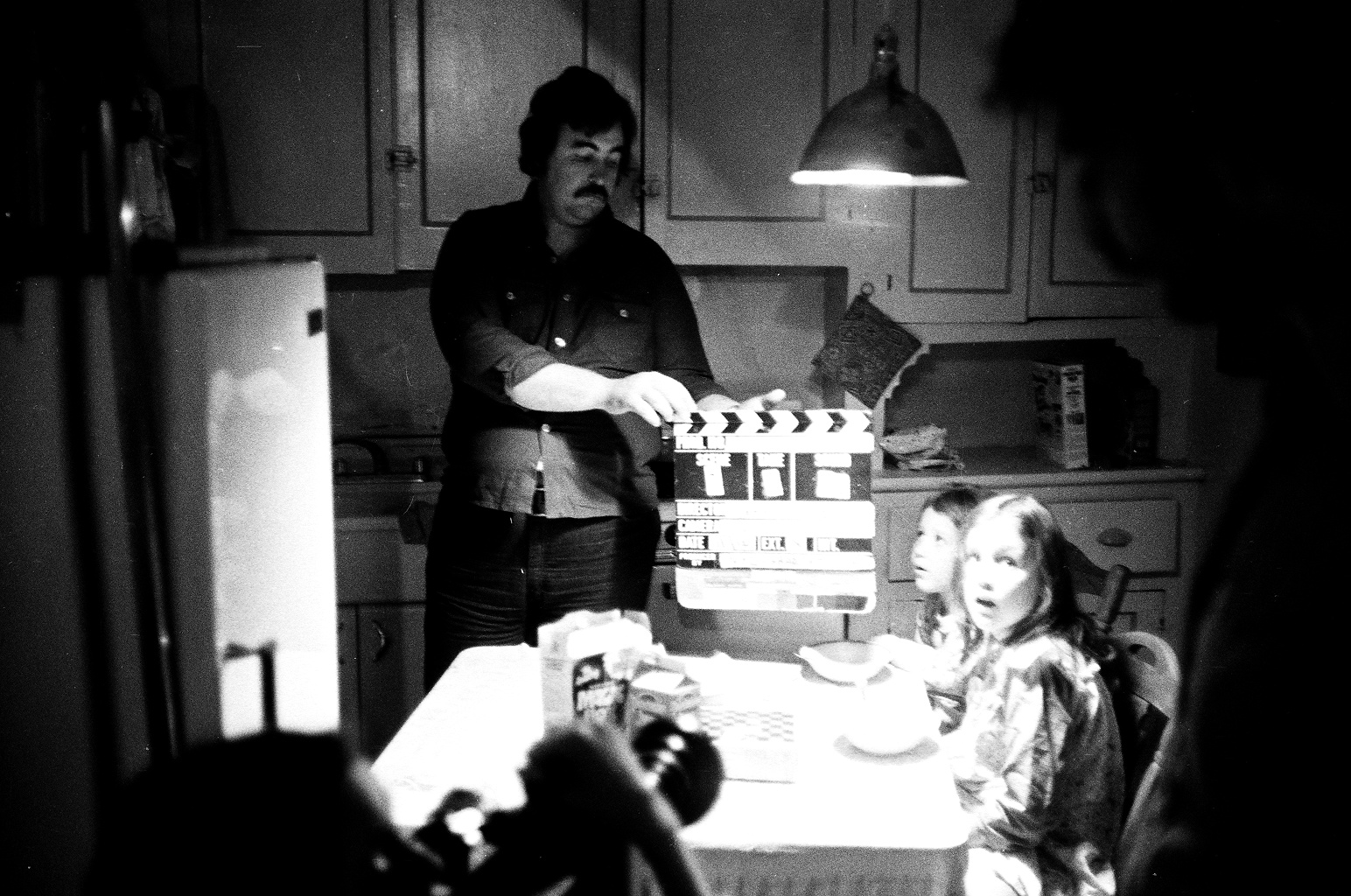 Actor William Reilly prepares movie slate for a scene during the making of Jeffrey Wisotsky's NYU student film, THE FORTUNE TELLER. Sitting at table are Jessica and Amanda Doherty.