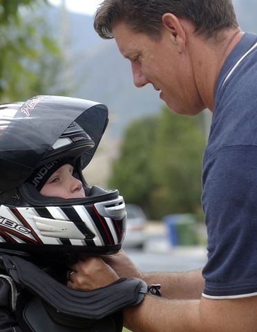 Hudson Morrow gets help with his helmet from his father, Chris.