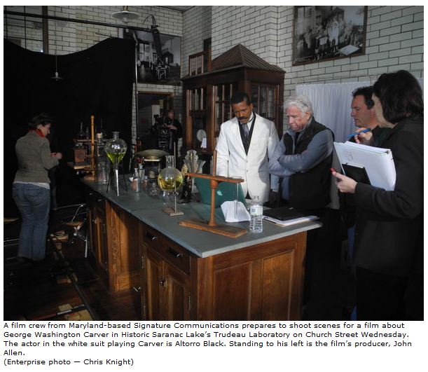 A film crew from Maryland-based Signature Communications prepares to shoot scenes for a film about George Washington Carver in Historic Saranac Lakes Trudeau Laboratory on Church Street Wednesday. The actor in the white suit playing Carver is Altorr