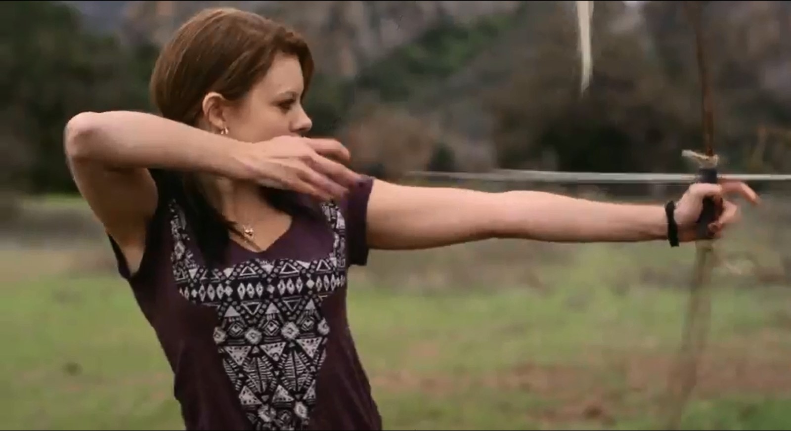 Tracey Fairaway as Kayla shooting off an arrow