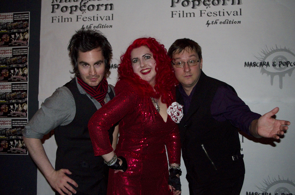 Photograph of Cassandra Sechler, Eric Falardeau, and Craig Jacobson at the black carpet ceremony for the 4th Annual Mascara and Popcorn Film Festival, 2013. http://www.mascaraandpopcorn.com/