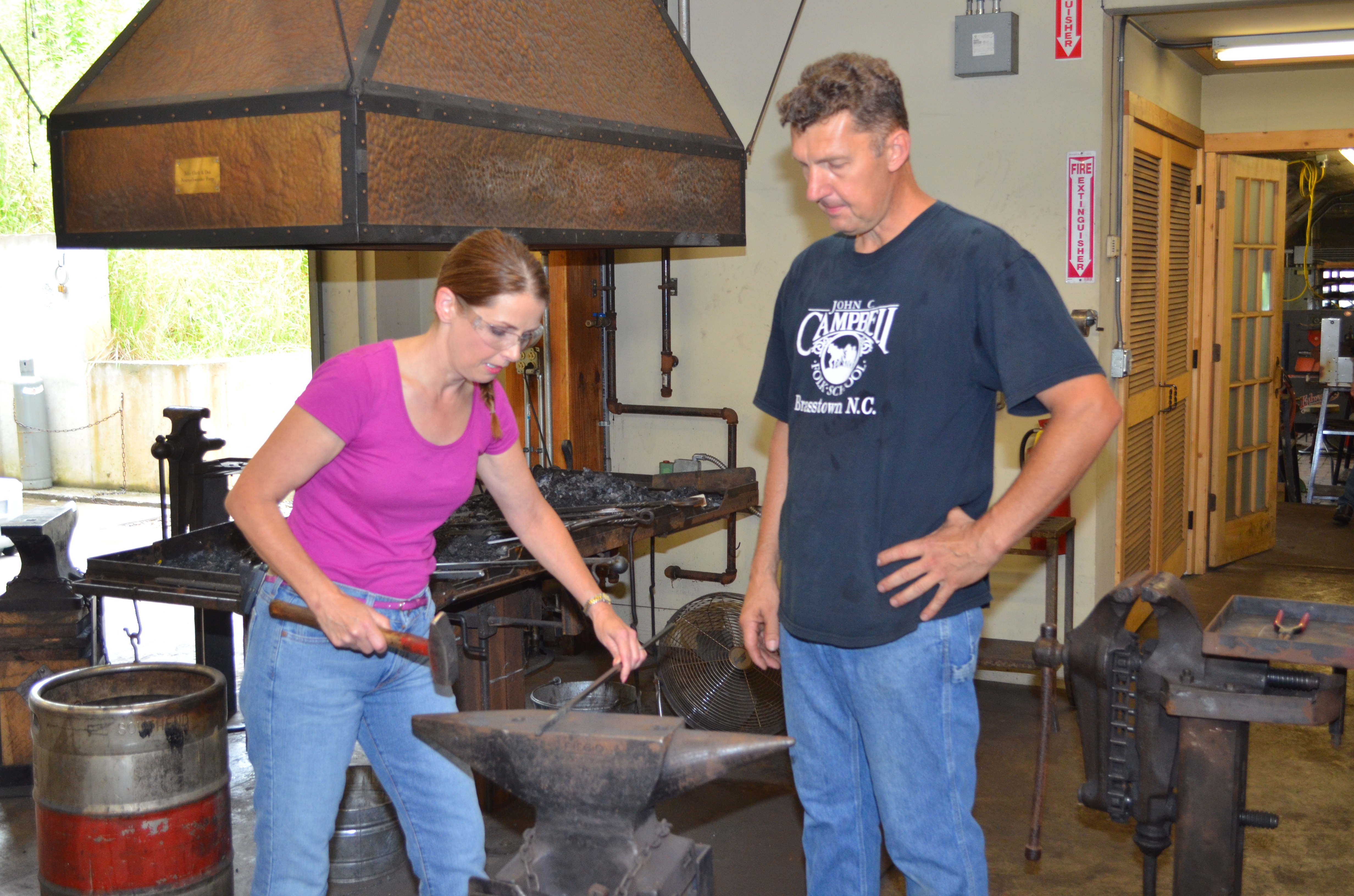 Ann Lukens interviewing blacksmith Paul Garrett and trying a hand at the hammer.
