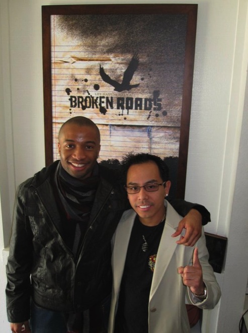 Rey and writer/director Justin Chambers in front of Broken Roads poster